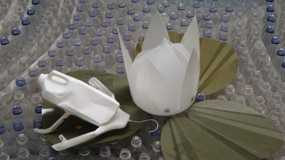 Something that looks like a frog made out of a milk container sitting on a cardboard lily at "Fragile" by Roadsworth and Brian Armstrong at the Eaton Centre. Something that looks like a frog made out of a milk container sitting on a cardboard lily at "Fragile" by Roadsworth and Brian Armstrong at the Eaton Centre.